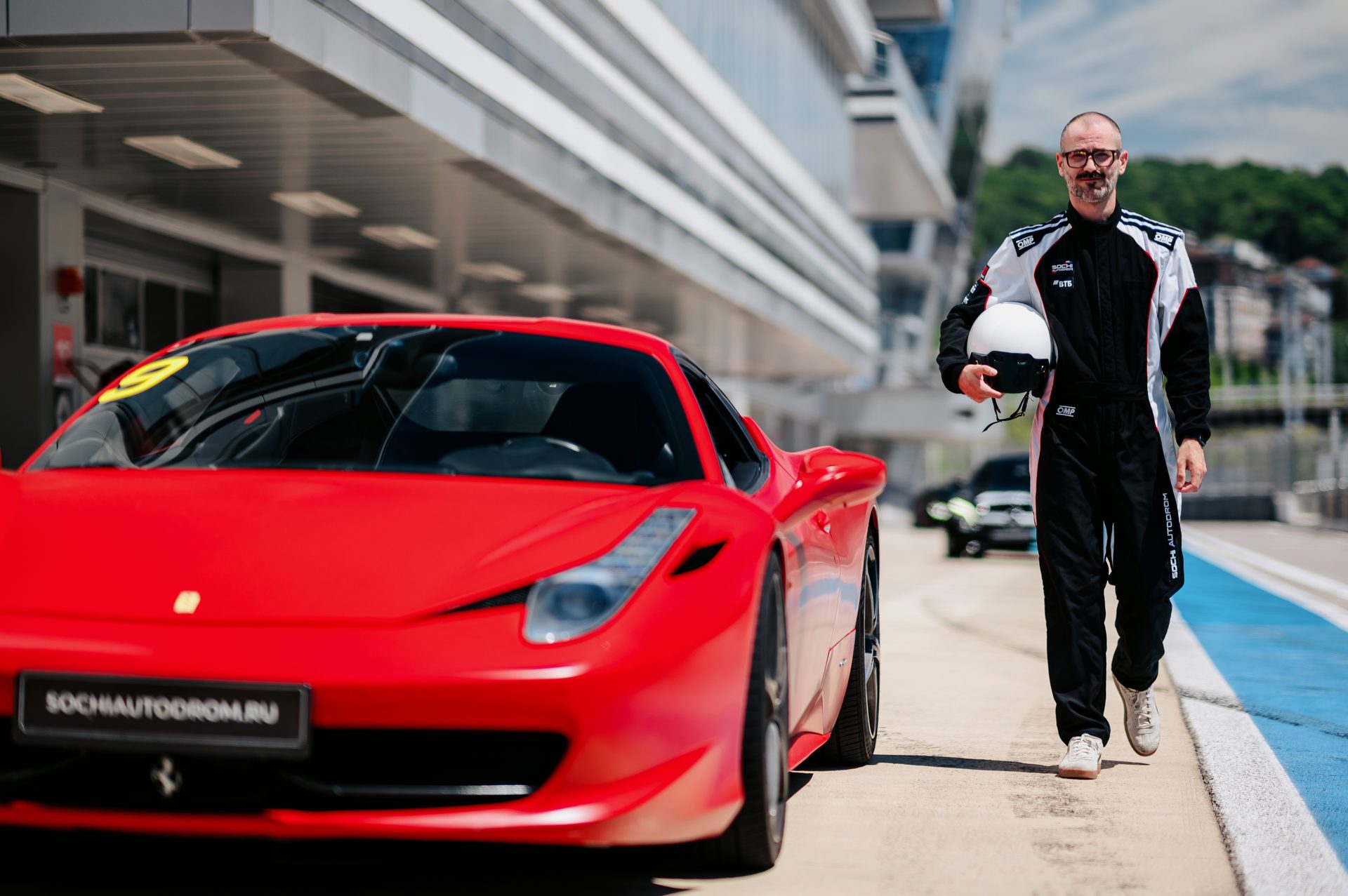 Пилот со шлемом и красный Ferrari на пит-лейне Сочи Автодрома